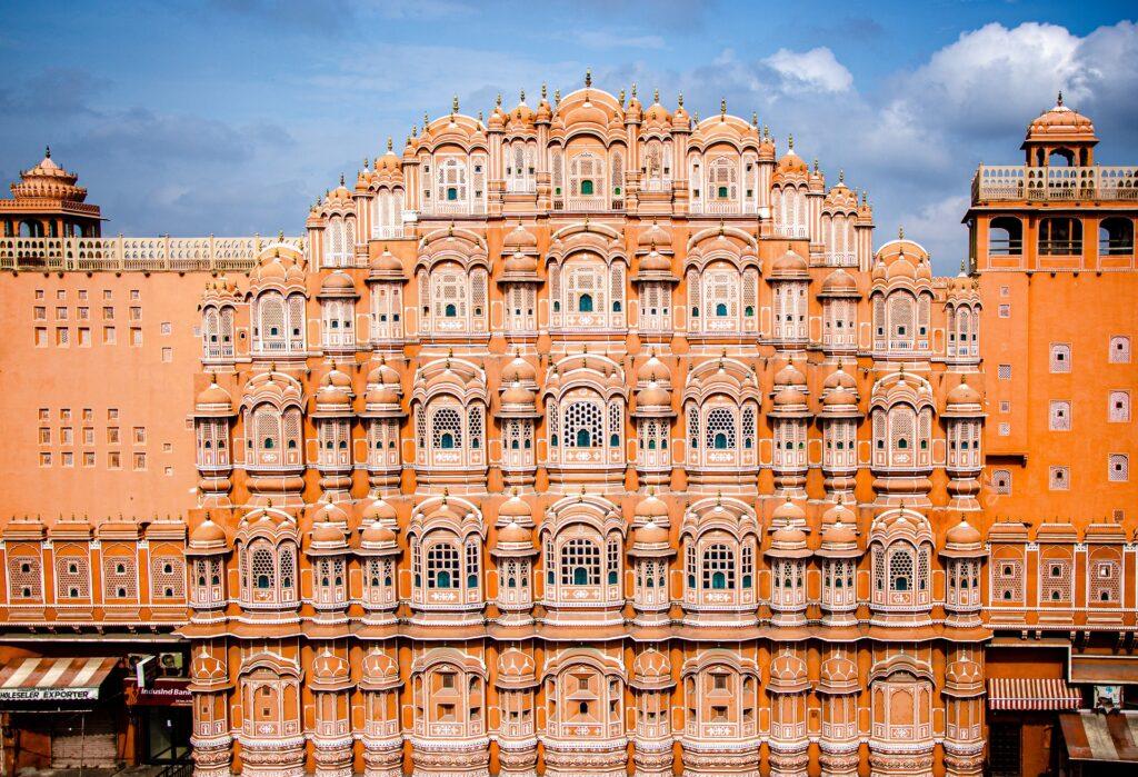 Image of the Hawa Mahal, a stunning five-story palace with pink sandstone and intricate latticework windows, featured in many popular ONE DAY DELHI TO JAIPUR TRIP PACKAGES.